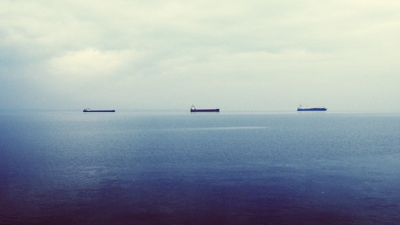 Cargo ships in a straight line following each other on the open ocean