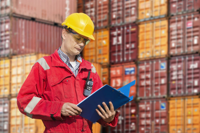 Man reading over document in a container yard