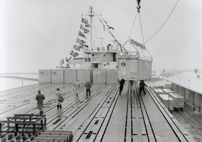 People loading the first container ship